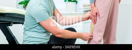 Young woman with lower back pain in physical therapy. Chiropractor examining female patient using measuring tape to determine mobility level. Stock Photo