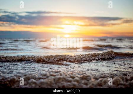 Close-up of ocean waves at sunset with golden reflections on water Stock Photo