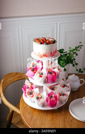 cupcakes and cake with berries on a stand Stock Photo