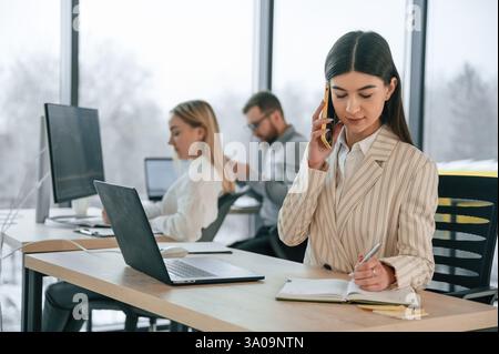 Woman talking by phone. Successful team are working together in the office. Conception of business. Stock Photo