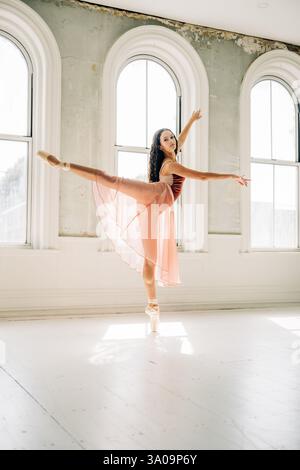 Ballerina performing an arabesque in soft natural light studio Stock Photo