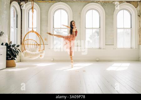 Ballerina performs an arabesque in a sunlit studio Stock Photo