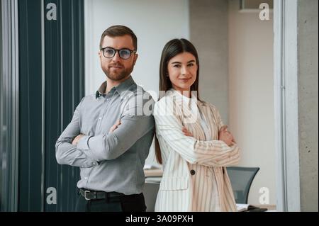 Man with woman is standing and posing. Successful team are working together in the office. Conception of business. Stock Photo