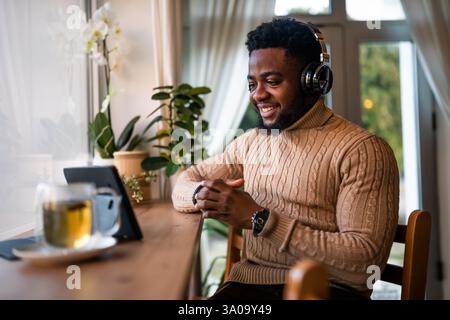Freelancer using digital tablet to communicate online. He is sitting in bar and having video call. Stock Photo