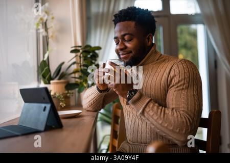 Young man using digital tablet to communicate online. He is sitting in bar,drinking tea and having video call. Stock Photo