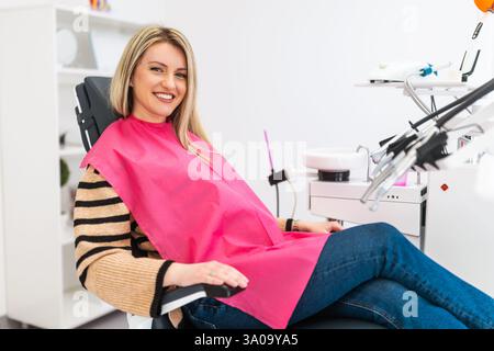 Happy young woman in modern dental clinic. She is looking at camera and smiling. Stock Photo