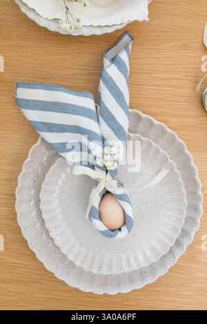 Easter egg wrapped in linen napkin in the shape of bunny with ears. Happy Easter  Stock Photo