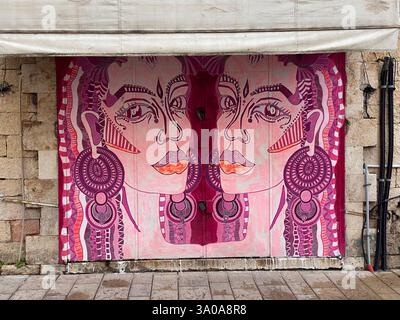 "Vibrant street art in Tel Aviv, Israel, depicting two abstract, tribal-inspired female figures on a rustic stone wall. This bold and expressive mural Stock Photo