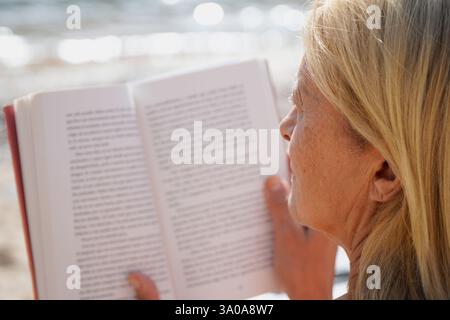 close up of a woman reading a book on the beach. World book day Stock Photo