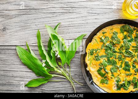 Spring omelette with fresh ramson or wild garlic leaves. Healthy spring diet food concept. Stock Photo