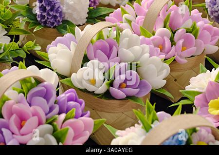 Small spring bouquets made of artificial flowers in wicker wooden baskets, close up shot, abstract background Stock Photo