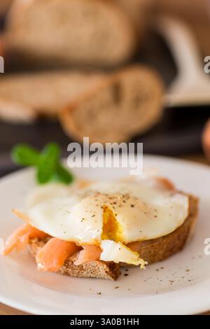 A slice of bread with a cooked egg and lightly salted red fish. Stock Photo
