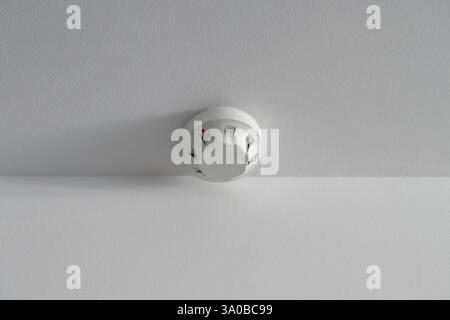 Safety engineering. Fire alarm sensor on white ceiling. Stock Photo