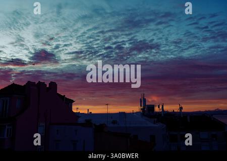 A dramatic Alfama sunset paints the sky in deep blues and fiery reds over the Lisbon rooftops Stock Photo