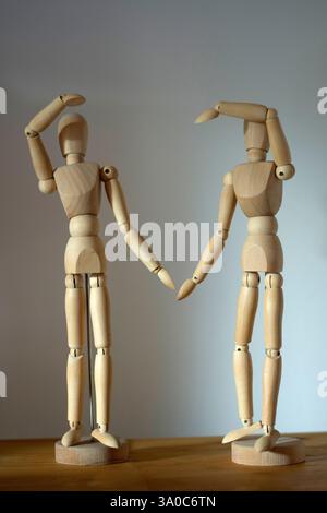 Couple of wooden mannequin figurines making heart shape with their arms Stock Photo