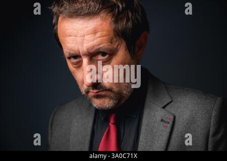 Portrait of serious and tired businessman in dark office, low key with selective focus Stock Photo