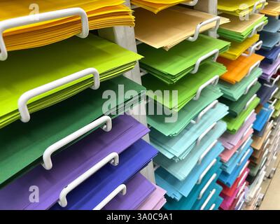 Colorful paper sheets are neatly stacked and arranged on shelves, creating a visually appealing display of vibrant colors Stock Photo