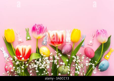 Spring Easter background, multi-colored Easter eggs and tulips with gypsophila on a pink background, copy space Stock Photo