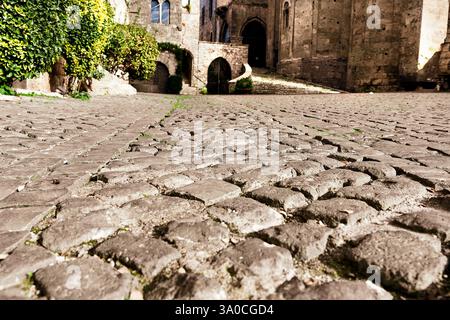 Ground-level view of the cobblestone pavement of a street at the foot of an ancient medieval cathedral Stock Photo