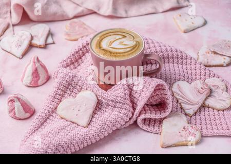 Cup of cappuccino with homemade decorated heart shaped cookies and other sweets on pink background, concept for valentine's day Stock Photo