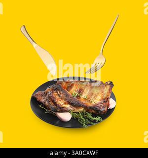 Cutlery in air over plate with tasty grilled ribs on golden background Stock Photo
