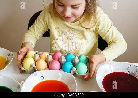 A happy girl proudly shows her beautifully colored Easter eggs after dyeing them at home Stock Photo