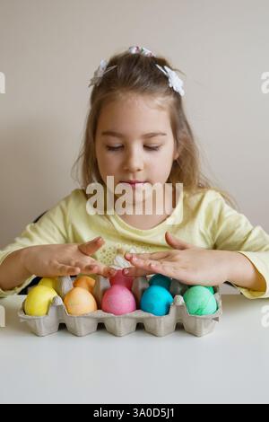 A happy girl proudly shows her beautifully colored Easter eggs after dyeing them at home Stock Photo