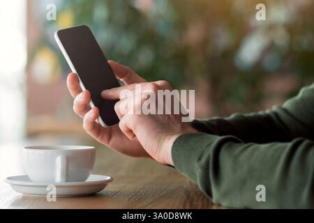 Cropped of man using smartphone at cafe Stock Photo