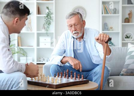 Senior man with his son playing chess at home Stock Photo