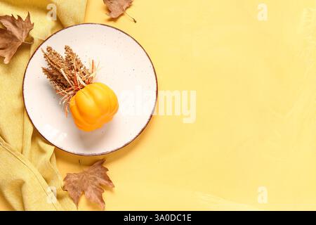 Stylish autumn table setting with dry maple leaves on yellow background Stock Photo