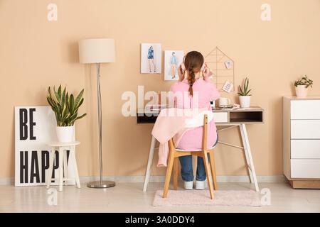 Female fashion designer sitting at table in office, back view Stock Photo