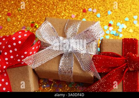Three gift boxes with different bows next to colorful hearts Stock Photo