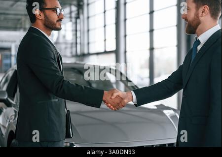 Two businessmen are working together in the car showroom. Stock Photo