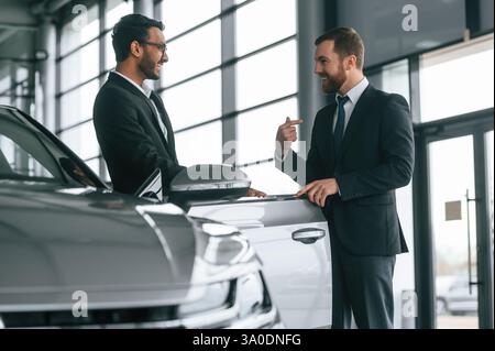 Two businessmen are working together in the car showroom. Stock Photo