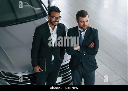 View from the top. Two businessmen are working together in the car showroom. Stock Photo