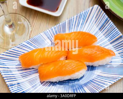 Blue rectangular ceramic plate of delicious salmon nigiri with soy souse on bamboo mat. Stock Photo