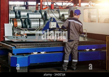 Worker operates mechanical vacuum lifter in metalworking factory. Stock Photo