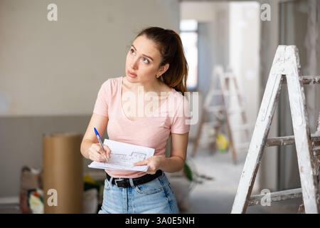Woman checking plan of house being renovated Stock Photo