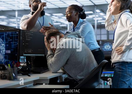 Employees berating engineer in office after mistake leading to errors in high tech AI data center. IT workers scolding admin in server farm after damaging artificial intelligence supercomputers Stock Photo