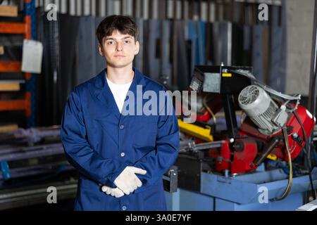 Young workman standing in front of pipe cutting machine in workshop Stock Photo