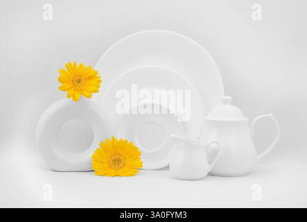 Crockery items displayed on a background with flowers. Still life photography Stock Photo