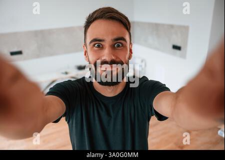 Happy funny man is making selfie in the domestic room. Stock Photo