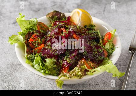 Beetroot salad with greens, tomatoes and dill on a stone table Stock Photo