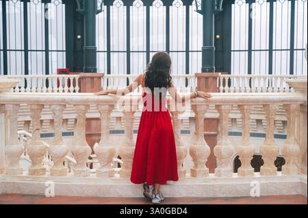 A romantic princess stands gracefully in a red dress inside an ancient castle. Stock Photo