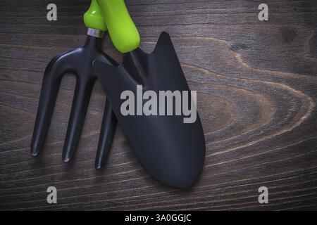 Black hand spade and trowel fork on vintage wooden board gardening concept Stock Photo