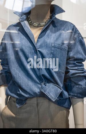 Casual fashion season summer clothes on female mannequins. Woman blue denim shirt on a mannequin in a display of a clothing store. Front view Light bl Stock Photo