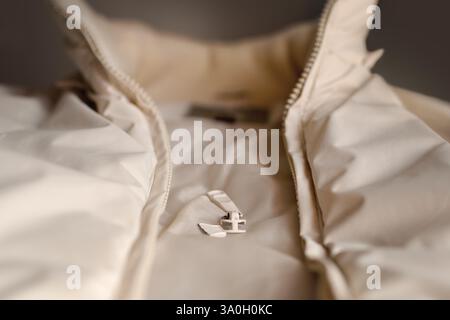 Close-up of a broken zipper on a light beige jacket. Details of the damaged runner, the texture of the fabric and knitted elastic. Stock Photo