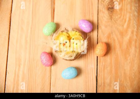 nest with yellow chickens and Easter patterned eggs. Decoration for Easter on a wooden background Stock Photo