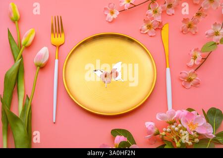 Golden plate decorated with mirror butterfly, which reflects pink spring flower, pink tulips, and cherry blossoms creating a vibrant spring compositio Stock Photo