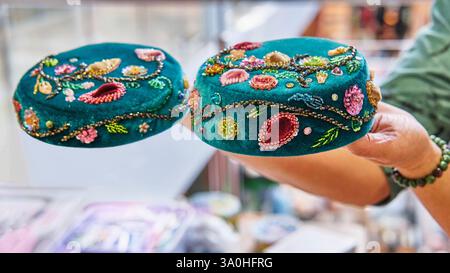 Womans hands holding two handcrafted Tatar skullcap with intricate floral bead embroidery, showcasing fine craftsmanship and cultural artistry. Stock Photo